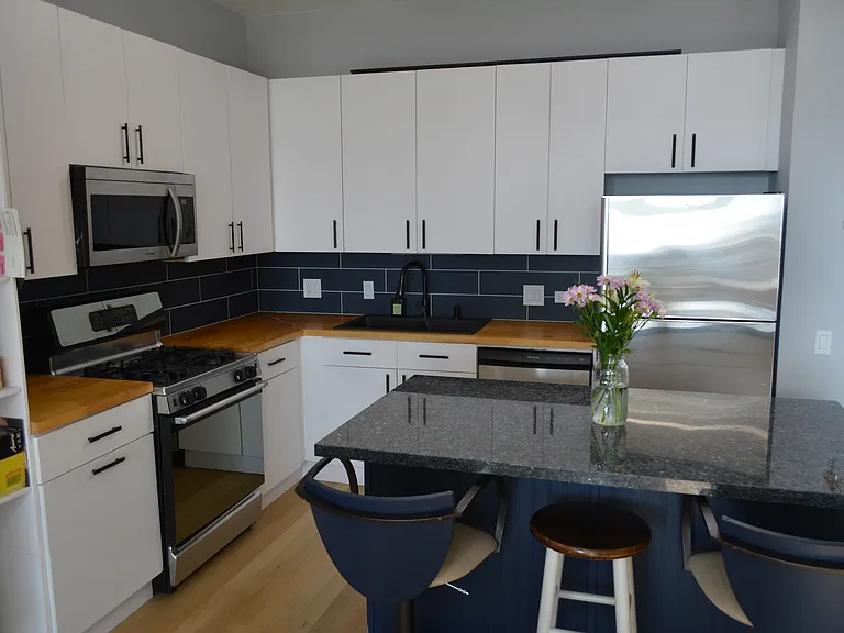 Sealed natural butcher block countertop with custom backslpash, three barstools for the island