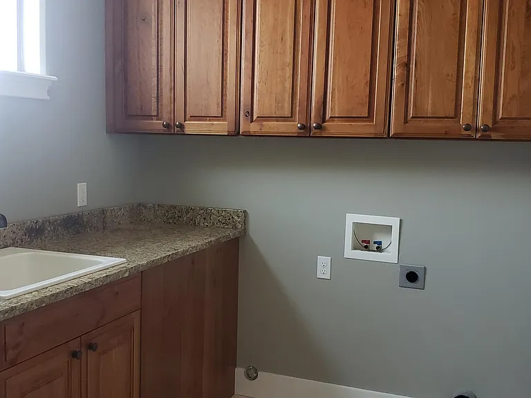 Sunny laundry room with lots of counters, storage cabinets and hookups.