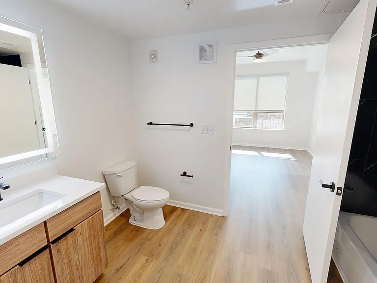 Apartment Bathroom with LED vanity mirror and Wood Style Flooring.