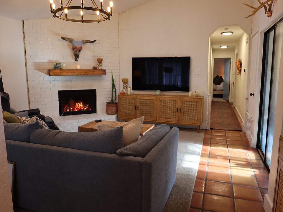 Open living room with brick fireplace, skylights and terra-cotta floors.