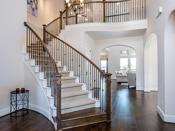 WOW! The beauty of this entryway is breathtaking! A curved wrought iron and wood baluster staircase leads up to the secondary living spaces, but the arched walkways and light bellowing from the formal dining and beyond into the family room beckons yo