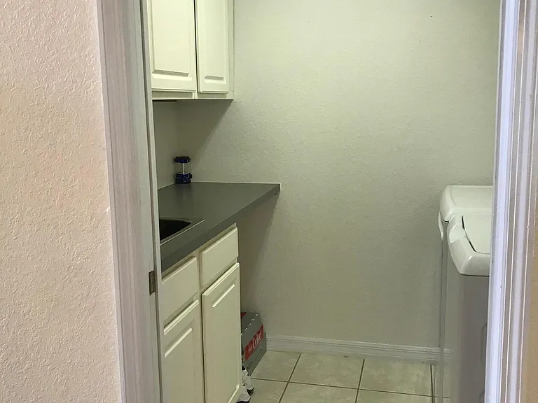 Separate laundry area with sink and cabinets.