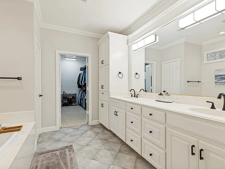 Bathroom featuring a double vanity with white cabinetry and countertops, matte black fixtures, an integrated soaking tub, and tiled flooring