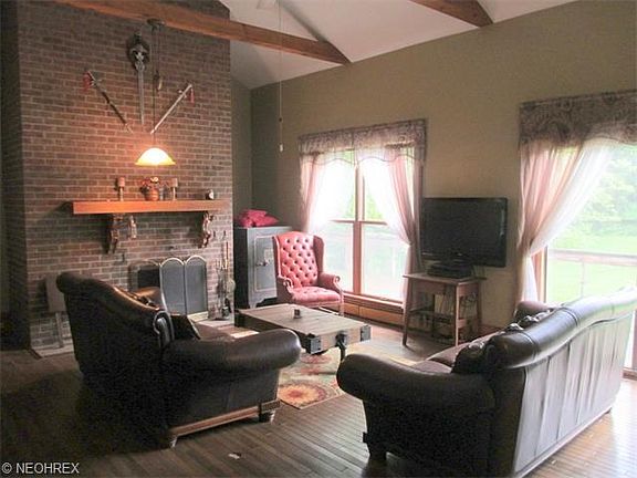 The living room highlighted by the fireplace, vaulted and beamed ceilings with a view of the pond