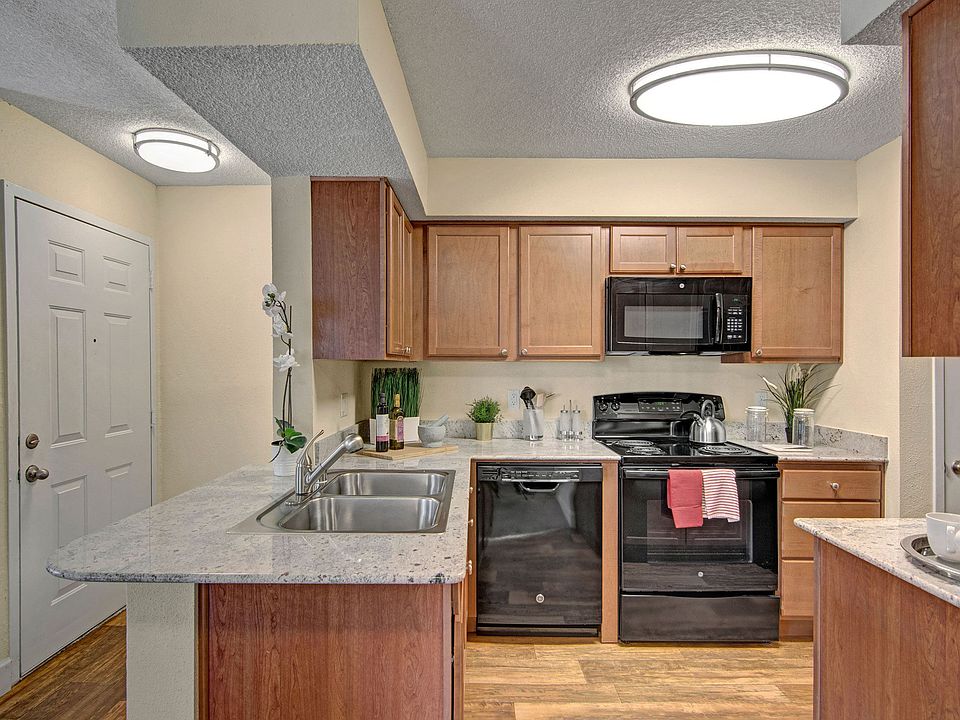A kitchen with light cabinets and black appliances