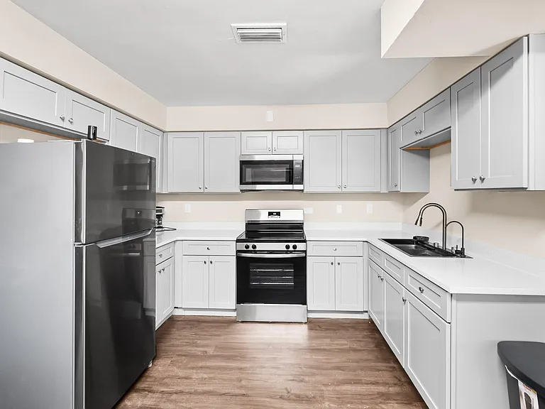 U-shaped kitchen with ample shaker cabinetry, generous counter space, and stainless range, microwave, and refrigerator.