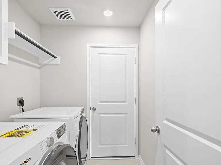 Interior utility room with Whirlpool washer and dryer included, upper shelving, and direct garage access.