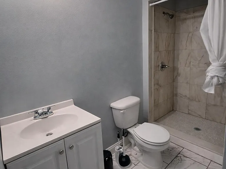 Updated full bath with single-sink vanity, ample counter space, and a walk-in tiled shower with curtain rod.