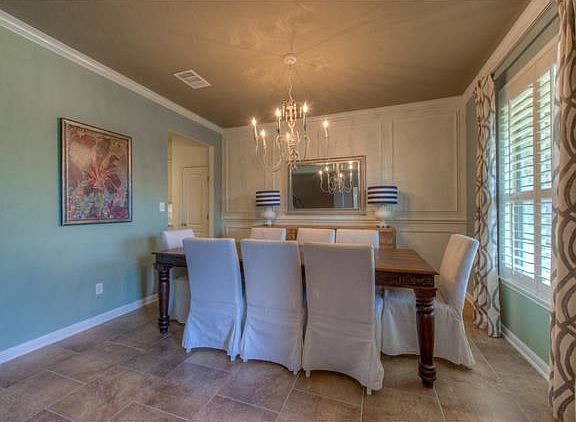 Natural light, crown molding, and immaculate tile floors create the perfect formal dining room for y