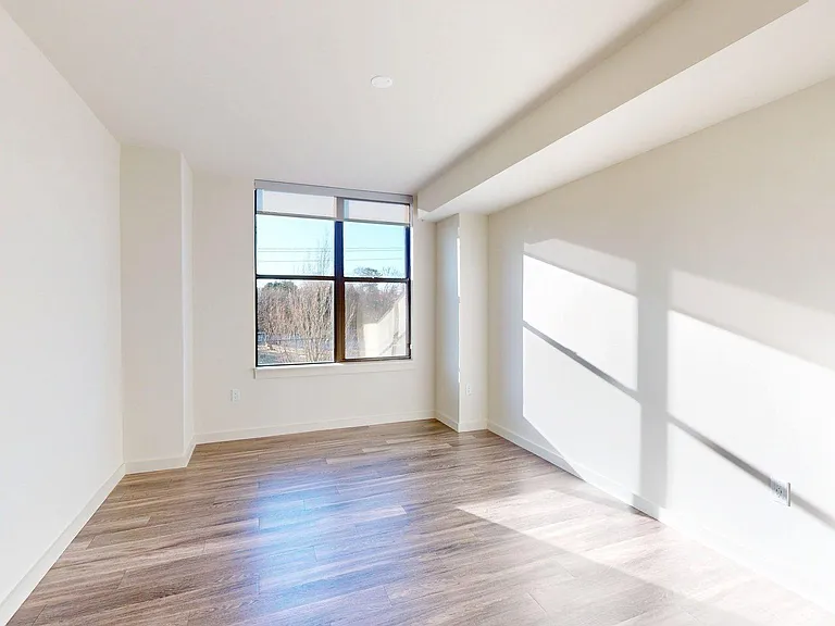 Spacious apartment bedroom with wood-style flooring.