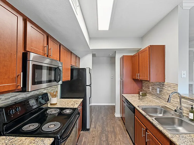 Classic Package I kitchen with stainless steel appliances, chestnut cabinetry, tile backsplash, speckled granite countertops, and hard surface flooring
