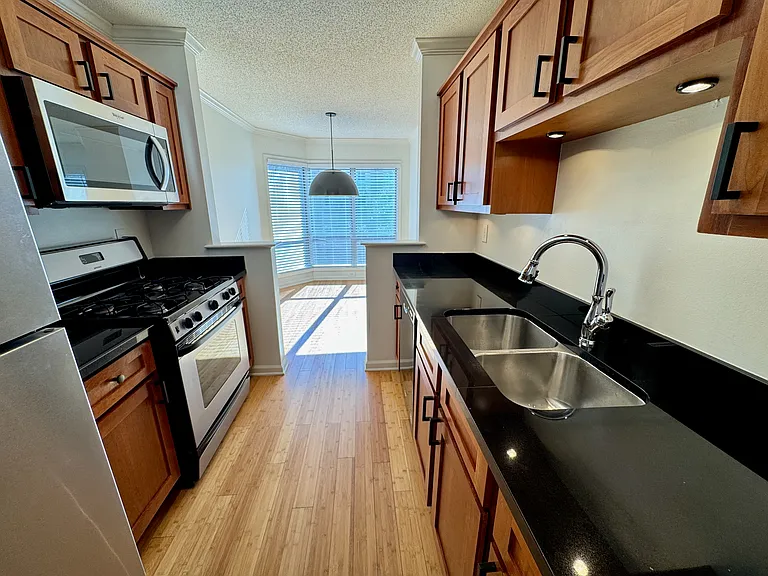 kitchen with cherry cabinets, granite counters, stainless/black appliances, dining room at end