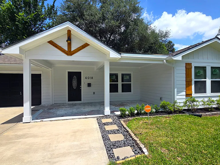Welcoming front porch with seating area, fresh landscaping, and tasteful accents like wood shutters. The driveway and pathway are well-maintained, offering great curb appeal.