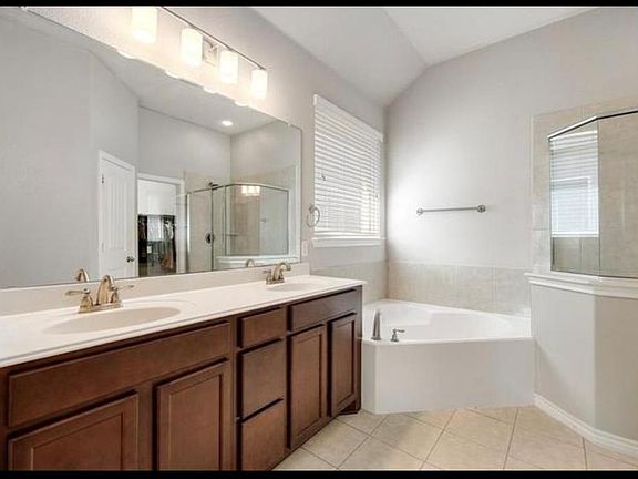 Full bathroom featuring light tile patterned flooring, a garden tub, a stall shower, and double vanity