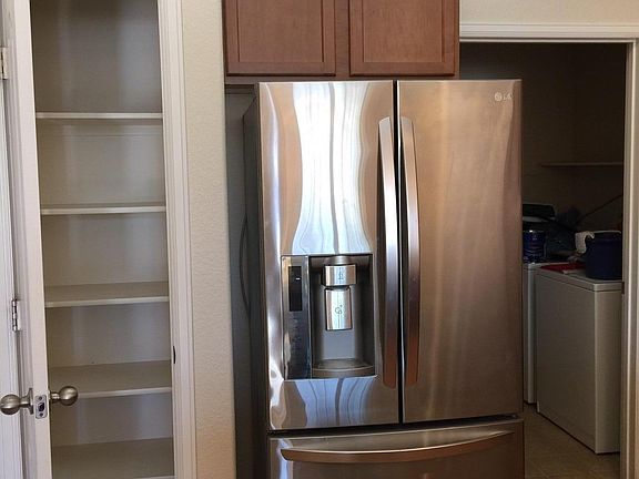 Pantry and new kitchen refrigerator. Laundry room in background