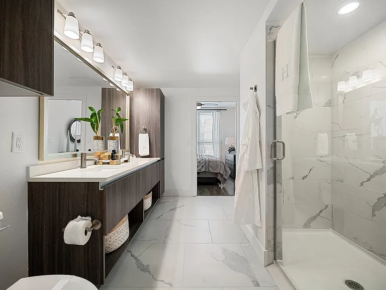 Bathroom with dual vanity, quartz counters, and glass shower