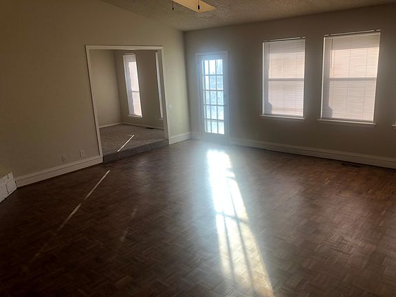 Part of the living room, 3 windows across the back look out to backyard, there are also three skylights, this room is very light and bright. Parquet flooring sanded and refinished, a nice area rug will warm this room up. You can see the entrance to the
