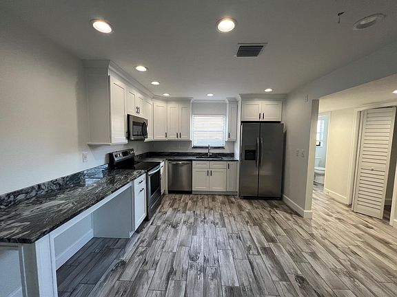 New open kitchen with white shaker board cabinets, stainless steel appliances and walk-in pantry.
