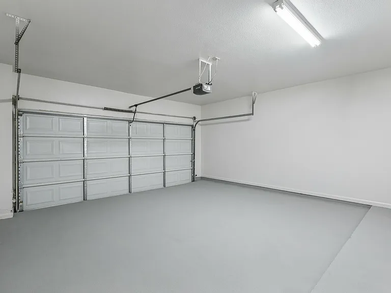 Spacious modern garage with clean white walls and an automatic door, perfect for storage and parking. Spacious modern garage with clean white walls and an automatic door, perfect for storage and parking.