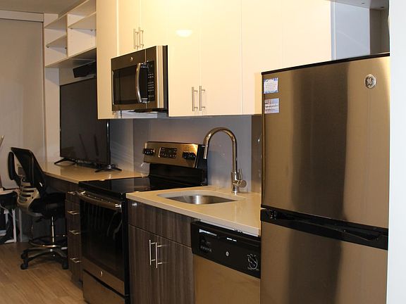 View from the front door; kitchen, desk/chair, and 60-inch smart TV