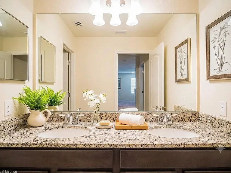Spacious double-sink vanity with granite countertop, oversized mirror, and ample storage, ideal for shared routines.