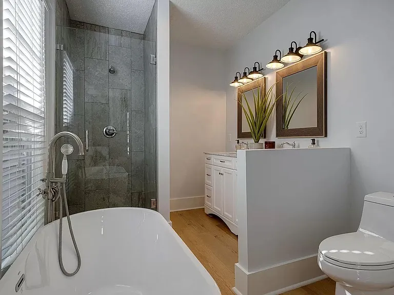 Master bath with duel vanity, bath tub, and rainfall shower.