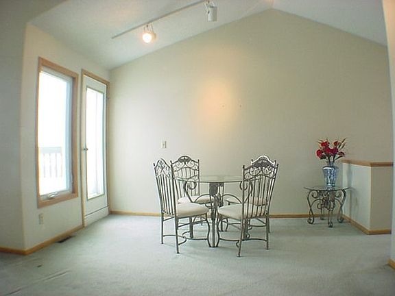 Vaulted dining room with track lighting and walkout to balcony