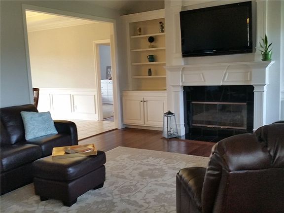 Large Great Room boasts hand scraped hardwoods, gas fireplace, custom built-ins & opens to Dining Room