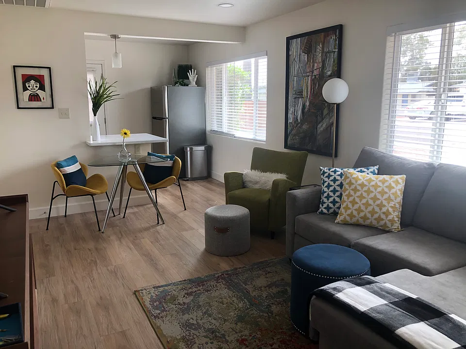 Living room into kitchen--staged with furniture. Tons of natural light, with blinds for privacy.