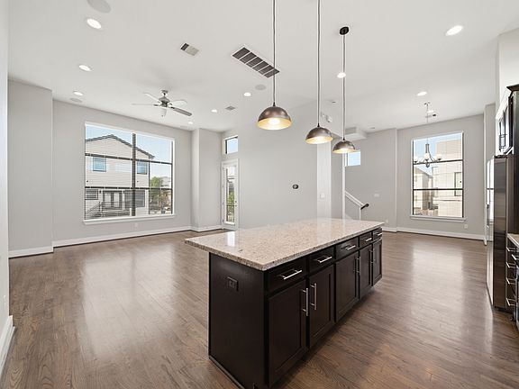 Open-concept living area showcasing rich hardwood floors, expansive windows that flood the space with natural light, and a stylish modern kitchen complete with a central island and elegant pendant lighting_perfect for both everyday living and entertaining