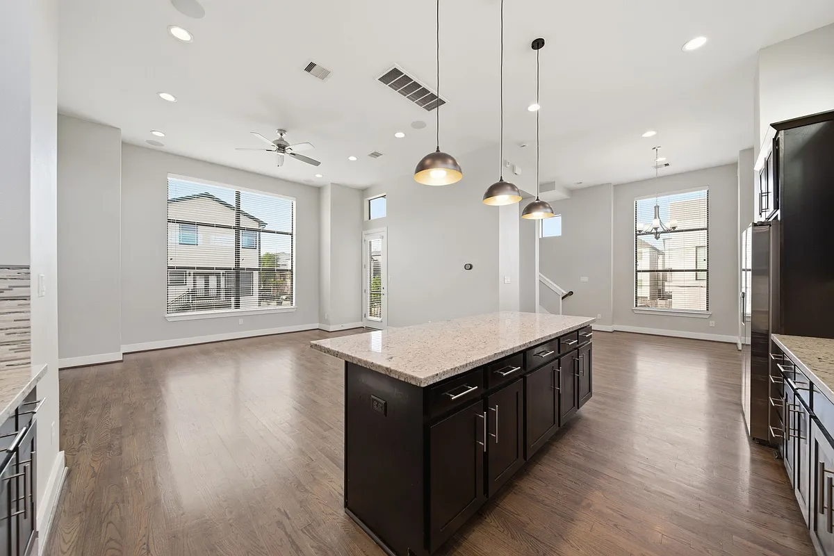 Open-concept living area showcasing rich hardwood floors, expansive windows that flood the space with natural light, and a stylish modern kitchen complete with a central island and elegant pendant lighting_perfect for both everyday living and entertaining - 1814 Thompson St