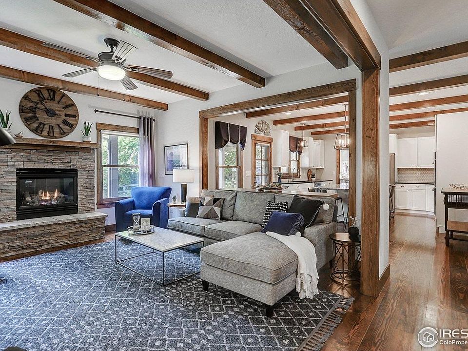 Open concept living room and kitchen with gas fireplace, high ceilings and custom wood beams.