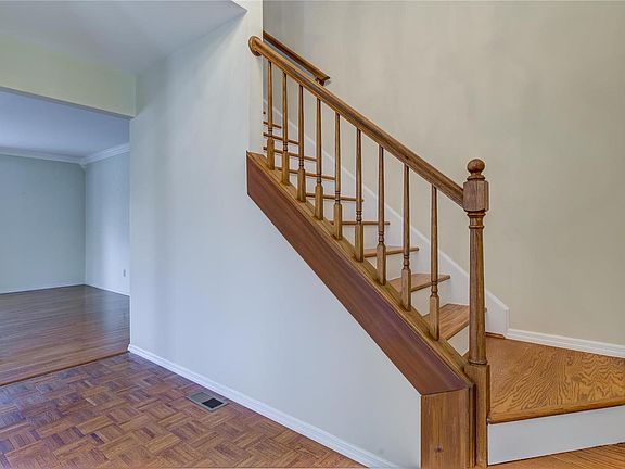 Entryway with wood floors and open stairway.