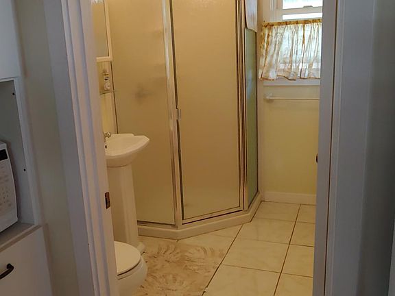 Full bathroom with corner shower & tile floors.
