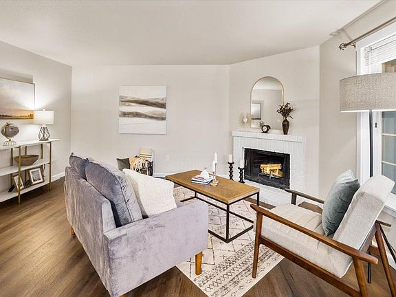 Spacious and bright living room has a cozy corner wood burning fireplace.