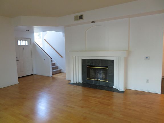 wood burning fireplace and view of front door and stairs to bedrooms