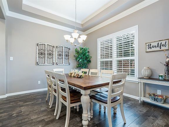 A formal dining room adorned with a tray ceiling, double crown molding and Plantations shutters is sure to be a great entertaining space for all that gather here!