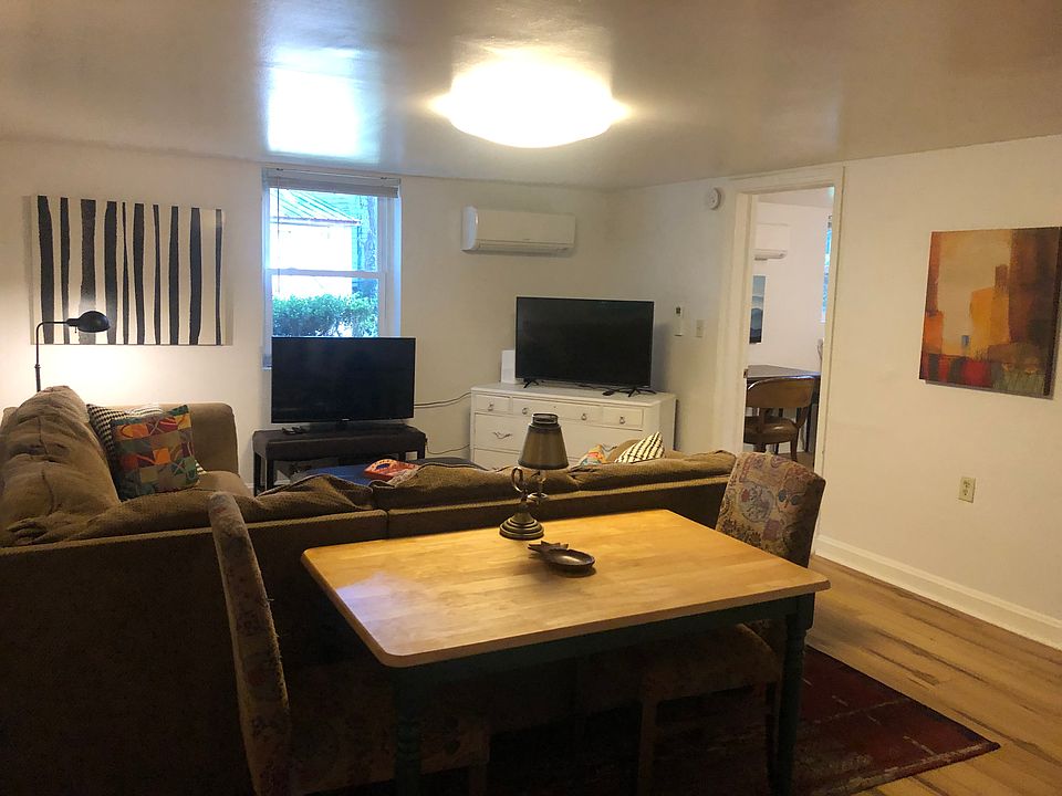 Large living room with comfortable sectional sofa and table for dining or workspace.