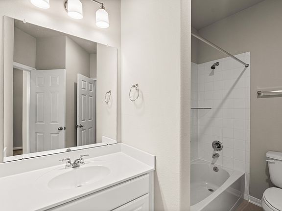 The secondary bath features tile flooring, white cabinetry and light countertops and a shower tub co