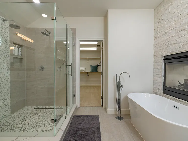 Modern ensuite with a glass shower, soaking tub, and fireplace