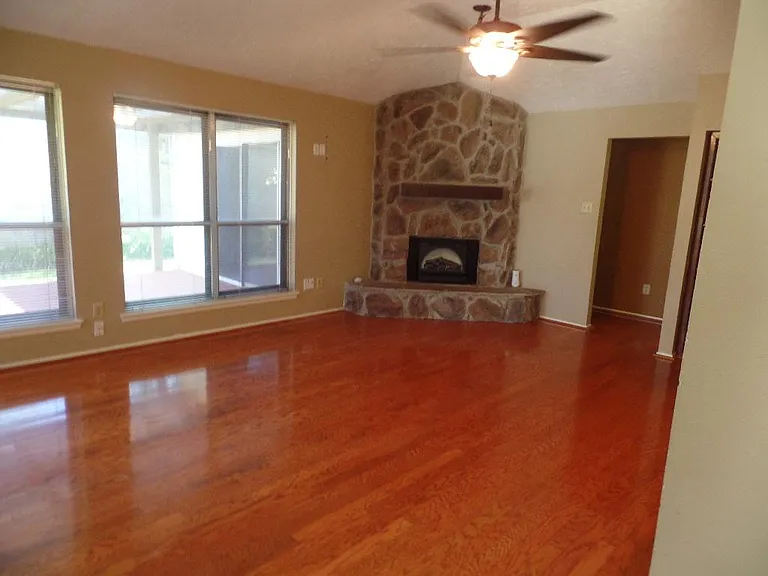 Living room with stone fireplace looking out to the beautiful landscape.