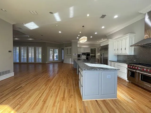 Kitchen featuring white cabinets, open floor plan, crown molding, pendant lighting, and high quality appliances