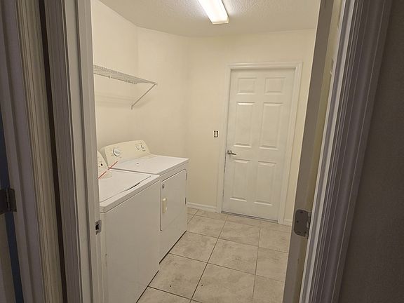 Dedicated laundry room with washer, dryer, upper shelf storage, and easy access to the garage.