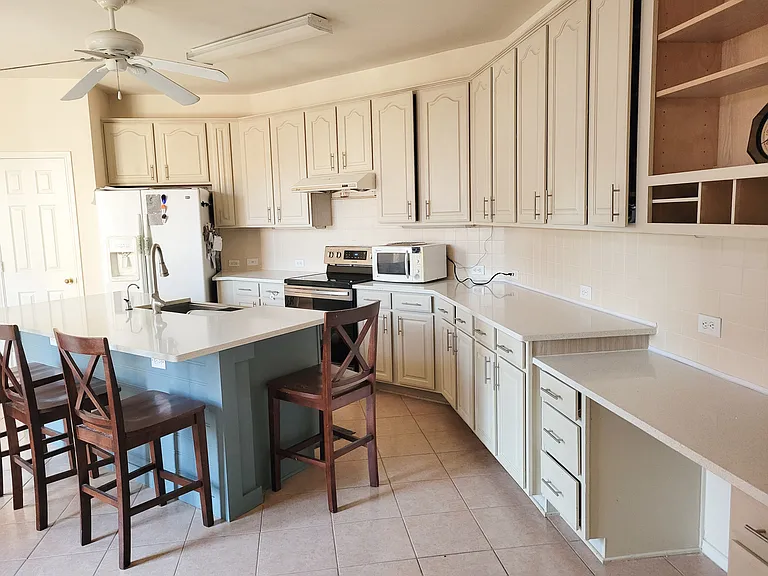 Kitchen with central 7 ft quartz counter top and fan and turbo vented out hood