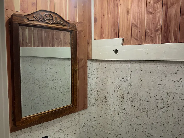 1st floor 1/2 bath featuring cedar boards, cork wallpaper and a vintage cabinet.