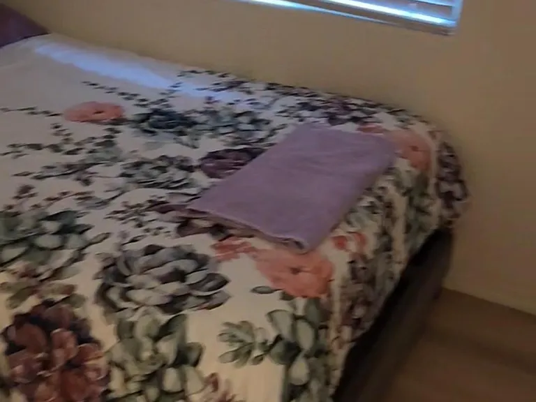 Furnished bedroom featuring a comfortable bed and a window with blinds for privacy and light control.