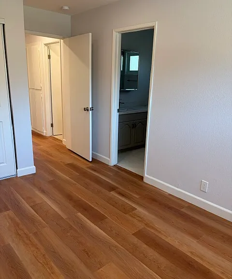 Upper level primary with view of ensuite bathroom and door to hallway