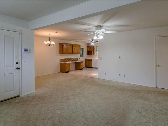 The door on the left is the front door - leads right in to the living room. The chandelier hangs over the dining area and the kitchen is visible just beyond. The door in the kitchen leads out to the garage and to an extra full bath.