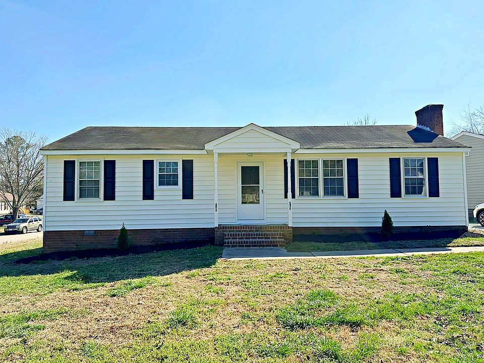 Front of the home with vinyl siding, freshly planted flower beds, new gravel in the driveway, all located on a large corner lot