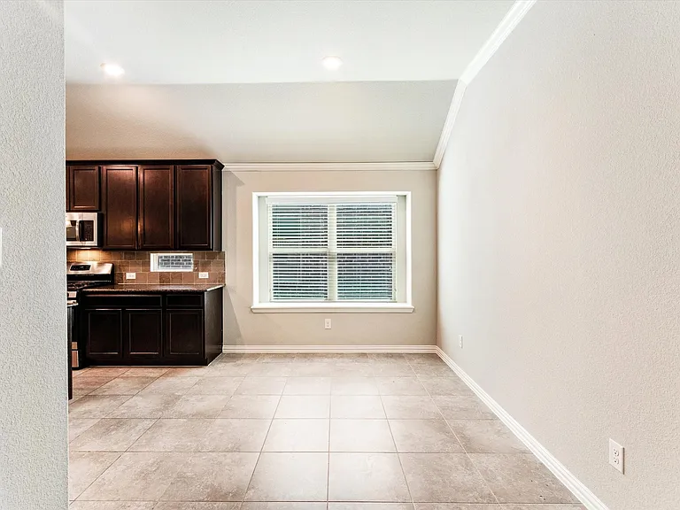 Kitchen area featuring dark wood-finish cabinetry, a ceramic tile backsplash, and stainless steel appliances
